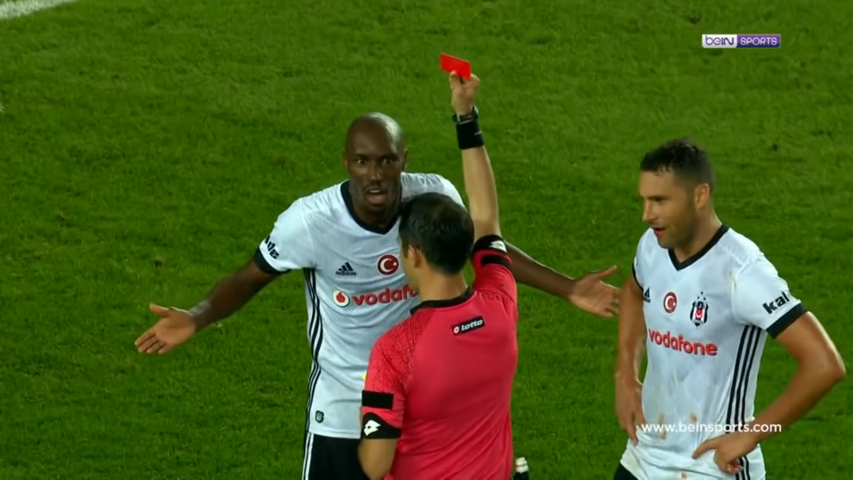 Árbitro mostrando tarjeta amarilla durante un partido nocturno